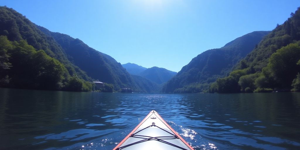 Kayaker paddling on calm water with green mountains in background.