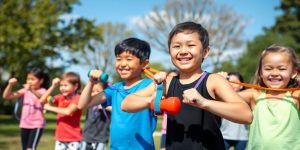 Kids exercising together with bands and weights outdoors.